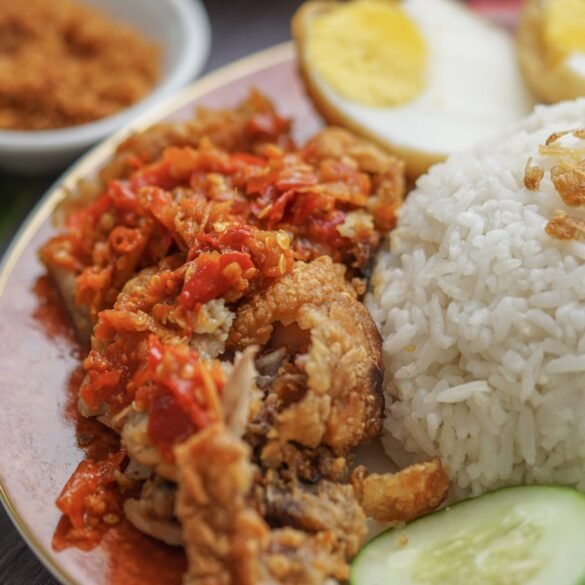 Tacho com arroz solto, pedaços de frango e cor escura do molho pardo